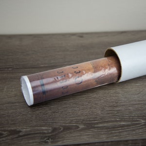 May include: A rolled up vintage-style world map in a white cardboard tube. The map is brown and has a faded look. The text "Pacific" is visible on the map.