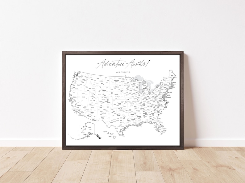 May include: A black and white map of the United States with all of the states labeled. The map is framed in a dark brown frame and the text "Adventure Awaits! Our Travels" is at the top of the map.