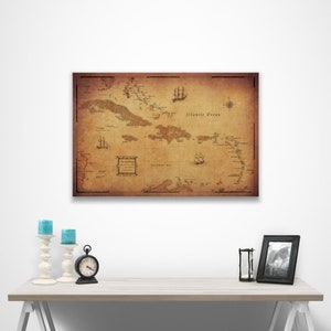 May include: An antique-style map of the Caribbean islands with a brown background and black text. The map shows the islands of the Caribbean Sea and the Atlantic Ocean. The map is framed and hanging on a white wall.
