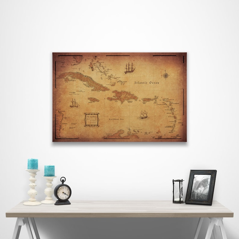 May include: An antique-style map of the Caribbean islands with a brown background and black text. The map shows the islands of the Caribbean Sea and the Atlantic Ocean. The map is framed and hanging on a white wall.