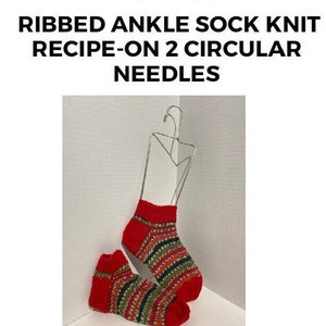 May include: Two pairs of red and green striped ankle socks knitted on two circular needles. The socks are hanging on a wire hanger.