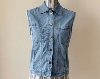 May include: A light blue denim vest with a button-up front and two pockets. The vest is sleeveless and has a collared neckline.