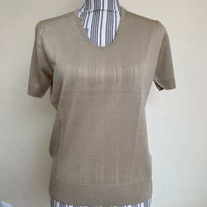 May include: A beige short-sleeved knitted top with a v-neck.