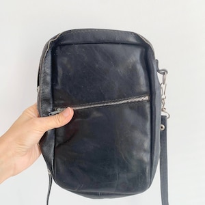 May include: A black leather crossbody bag with a silver zipper and chain strap.