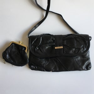 May include: Black leather crossbody bag with a gold clasp and a gold logo that says "STEFANOR". The bag has a quilted design and comes with a matching black leather coin purse.