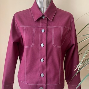May include: A maroon denim jacket with white stitching and silver buttons.