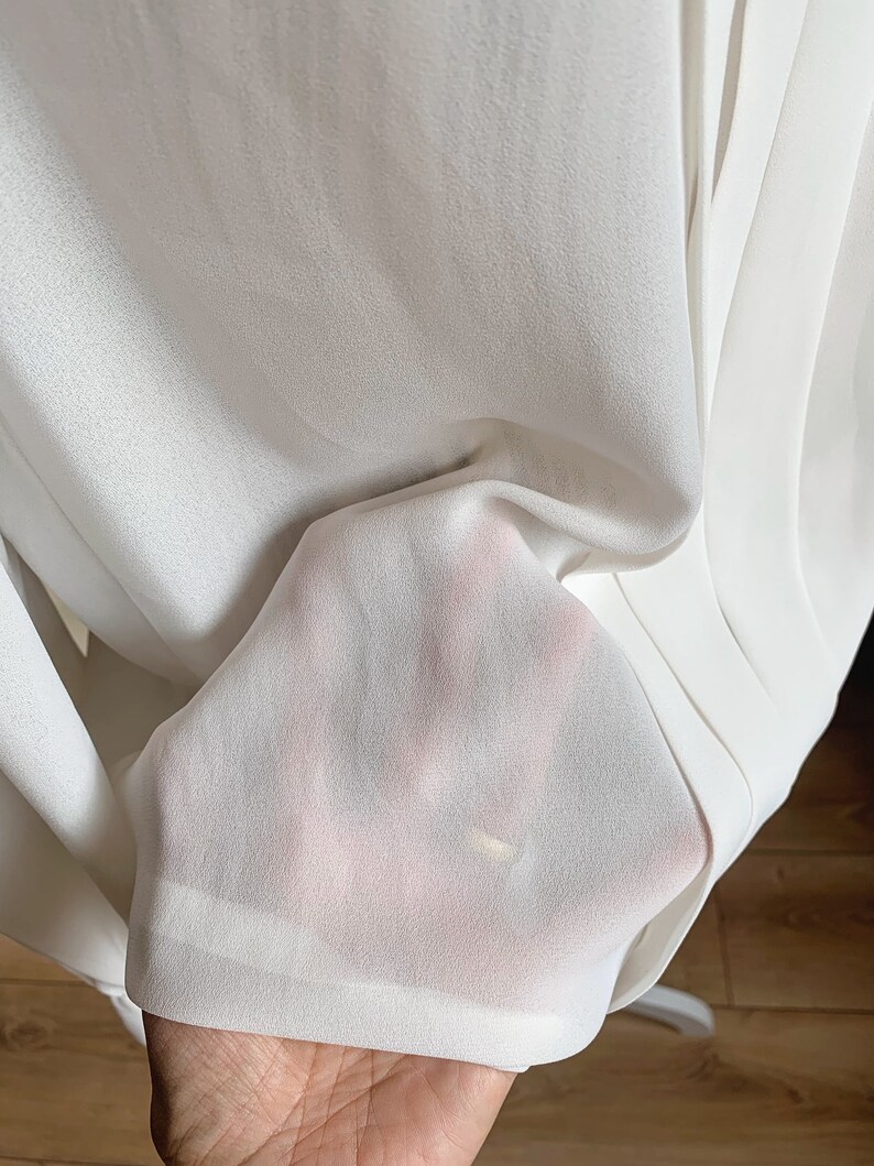 Puede incluir: Tela blanca transparente con una textura suave. La tela est&aacute; doblada y drapeada, mostrando su naturaleza delicada y fluida.