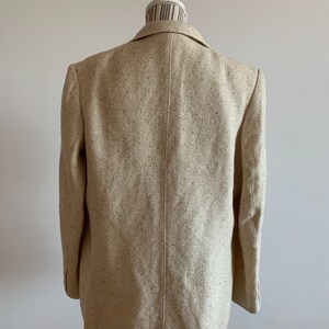 Peut inclure: Un blazer beige &agrave; texture mouchet&eacute;e. Le blazer est de style classique &agrave; double boutonnage avec un col crant&eacute;.
