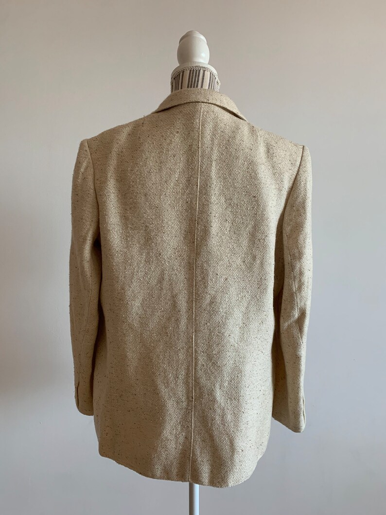 Peut inclure: Un blazer beige &agrave; texture mouchet&eacute;e. Le blazer est de style classique &agrave; double boutonnage avec un col crant&eacute;.