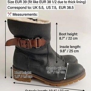 May include: A black leather ankle boot with a brown buckled strap and cream-coloured lining. Text indicates size EUR 39, boot height 22 cm, insole length 25 cm, heel height 4.5 cm, and outsole length 27 cm with a 9.5 cm outsole width.