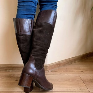 May include: Brown leather and suede knee-high boots with a block heel.