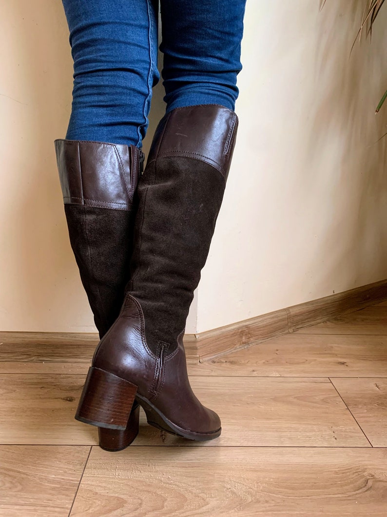 May include: Brown leather and suede knee-high boots with a block heel.