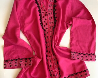 Op de afbeelding: Een roze overhemd met lange mouwen met zwarte borduursels rond de hals, manchetten en zoom. De borduursels hebben een geometrisch patroon.