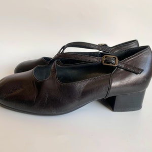 Pu&ograve; includere: Scarpe con tacco in pelle nera con cinturino con fibbia e design a cinturino incrociato.