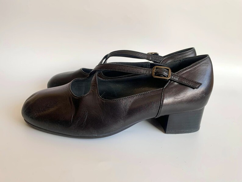Pu&ograve; includere: Scarpe con tacco in pelle nera con cinturino con fibbia e design a cinturino incrociato.