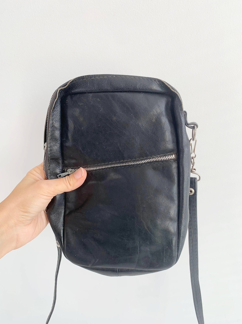 May include: A black leather crossbody bag with a silver zipper and chain strap.