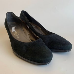 May include: A pair of black suede heeled shoes. The shoes have a pointed toe and a low heel.