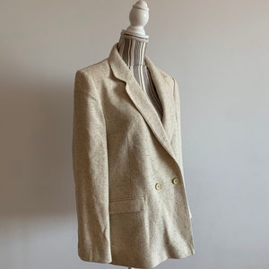 Peut inclure: Un blazer beige &agrave; double boutonnage avec un motif mouchet&eacute;.