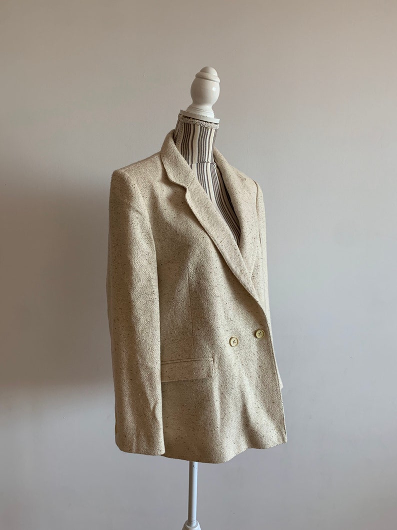 Peut inclure: Un blazer beige &agrave; double boutonnage avec un motif mouchet&eacute;.