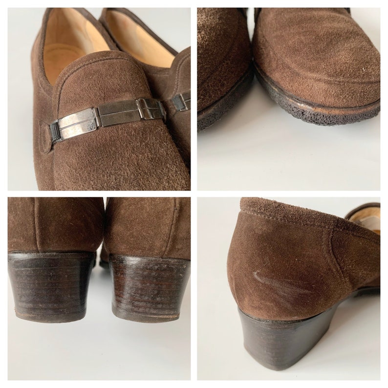 May include: Brown suede heeled loafers with a silver buckle detail. The shoes have a low block heel and a pointed toe.