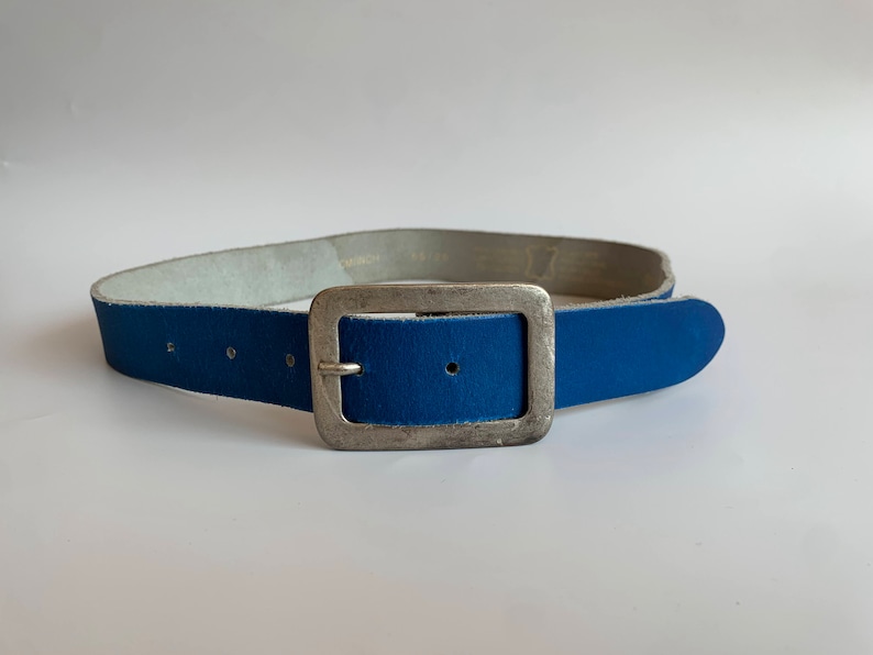 Pu&ograve; includere: Una cintura in pelle blu con una fibbia argentata.