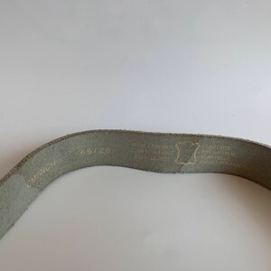Pu&ograve; includere: Una cintura in pelle grigia chiaro con il testo "65/26 CM/INCH" e "1208" stampato su di essa. La cintura ha anche il testo "GENUINE LEATHER, CONVERTIBLE, REAL LEATHER, ECHT LEDER" stampato su di essa.