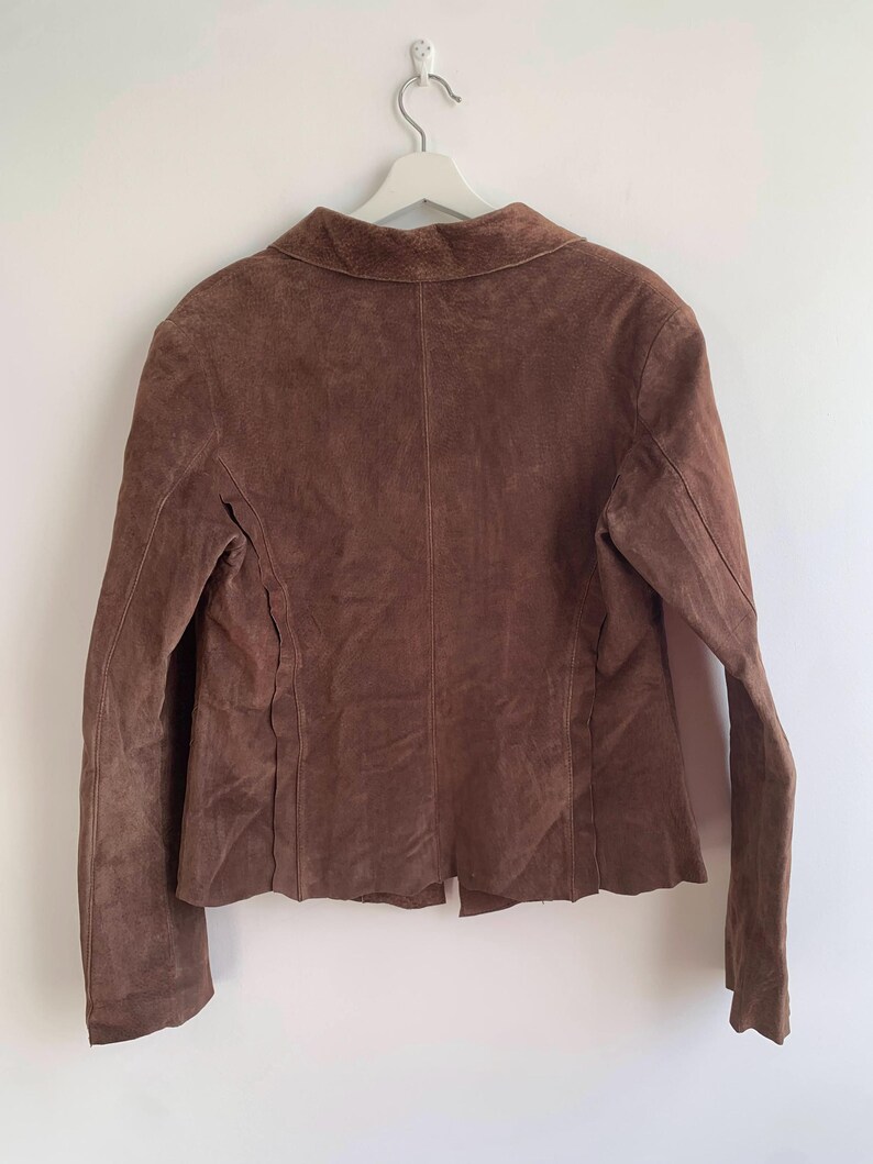 May include: A brown suede jacket with a collared neckline and long sleeves.
