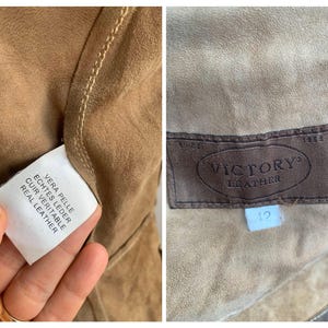 Op de afbeelding: Close-up van de binnenkant van een bruine leren jas. De jas heeft een bruin leren label met de tekst "VICTORY LEATHER" en een maat 12 label. Een wit label met "REAL LEATHER" is ook zichtbaar.