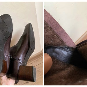 May include: A pair of brown leather ankle boots with a block heel. The boots have a zipper on the inside of the ankle and a brown suede lining.