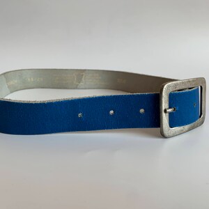 Pu&ograve; includere: Una cintura in pelle blu con una fibbia argentata. La cintura &egrave; realizzata in pelle morbida e flessibile e ha un design semplice e classico.