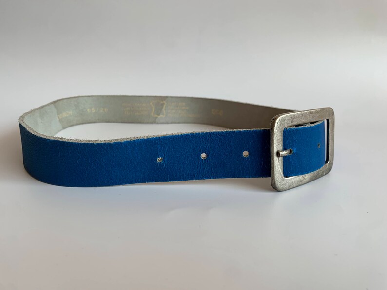 Pu&ograve; includere: Una cintura in pelle blu con una fibbia argentata. La cintura &egrave; realizzata in pelle morbida e flessibile e ha un design semplice e classico.
