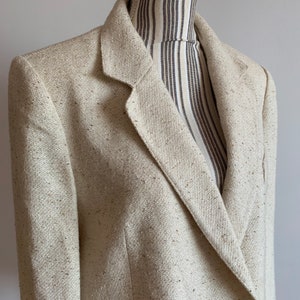 Peut inclure: Un blazer cr&egrave;me avec une fermeture &agrave; double boutonnage et un tissu textur&eacute;. Le blazer a un style classique et est fait d'un mat&eacute;riau l&eacute;ger.