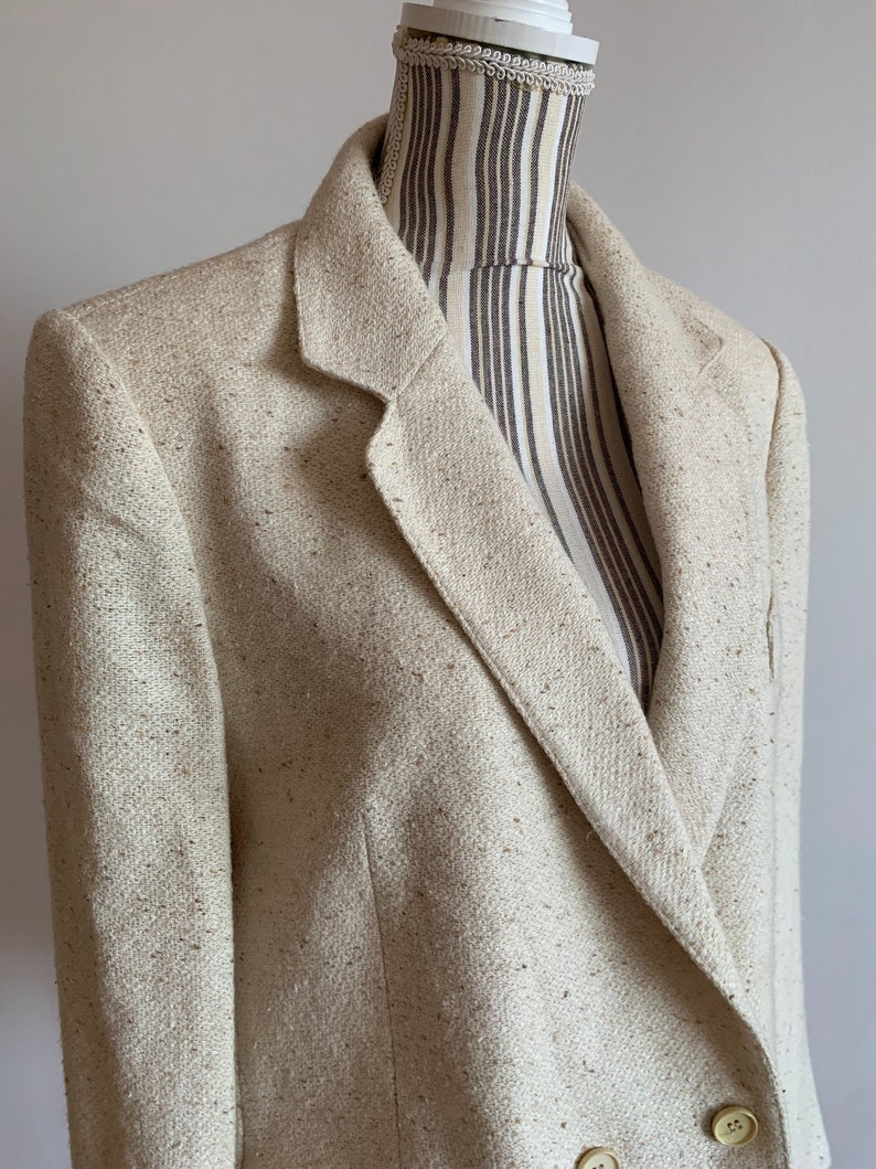 Peut inclure: Un blazer cr&egrave;me avec une fermeture &agrave; double boutonnage et un tissu textur&eacute;. Le blazer a un style classique et est fait d'un mat&eacute;riau l&eacute;ger.