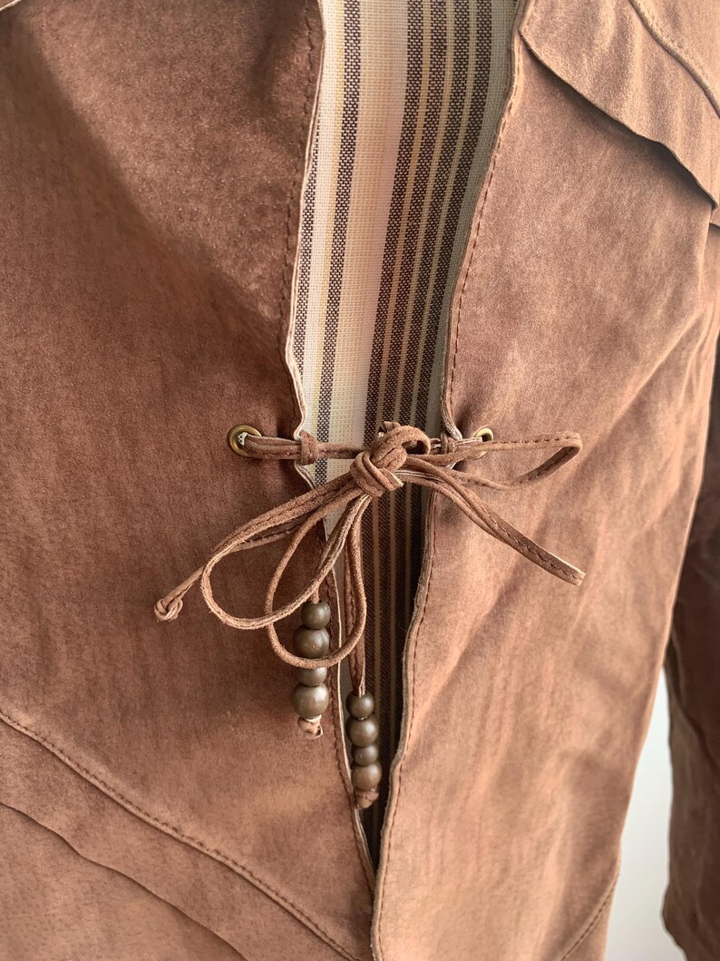 May include: A brown suede jacket with a striped fabric lining and a tie closure with wooden beads.