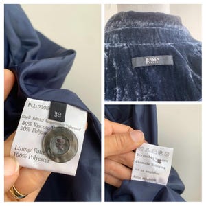 May include: Close-up of a navy blue velvet jacket with a tag that reads "JENSEN WOMEN". The jacket has a button and a tag with fabric composition and size 38. Care instructions are also visible.