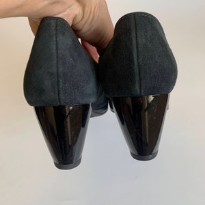 May include: A pair of black suede heeled shoes with black patent leather heels.