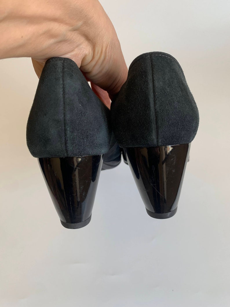 May include: A pair of black suede heeled shoes with black patent leather heels.
