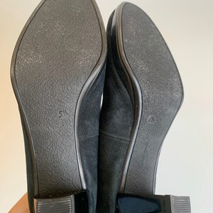 May include: A pair of black suede heeled shoes with a black patent leather heel. The shoes are size 5 1/2.