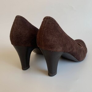 May include: A pair of brown suede heeled shoes with a pointed toe.