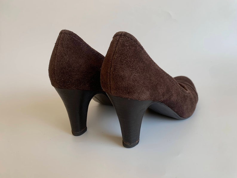 May include: A pair of brown suede heeled shoes with a pointed toe.