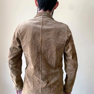 May include: A brown suede jacket with a button-up front and long sleeves.