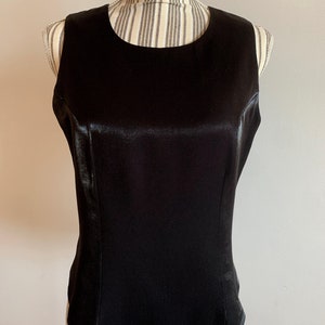 May include: A sleeveless black satin top with a round neckline.