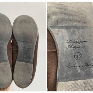 May include: Pair of brown suede flats. The soles are gray with the text "Lavorazione Artigiana", size 38, and "Made in Italy". The shoes are a neutral color and appear to be unworn.