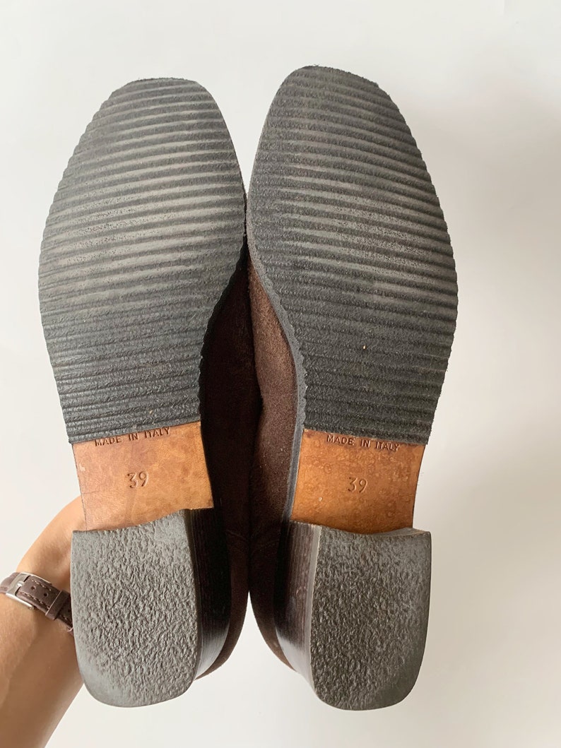 May include: A pair of brown suede ankle boots with a block heel. The boots are size 39 and say "Made in Italy" on the soles.