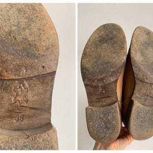 May include: Close-up of the soles of two brown leather shoes. The shoes have a worn look and are marked "Made in Italy" and "36".