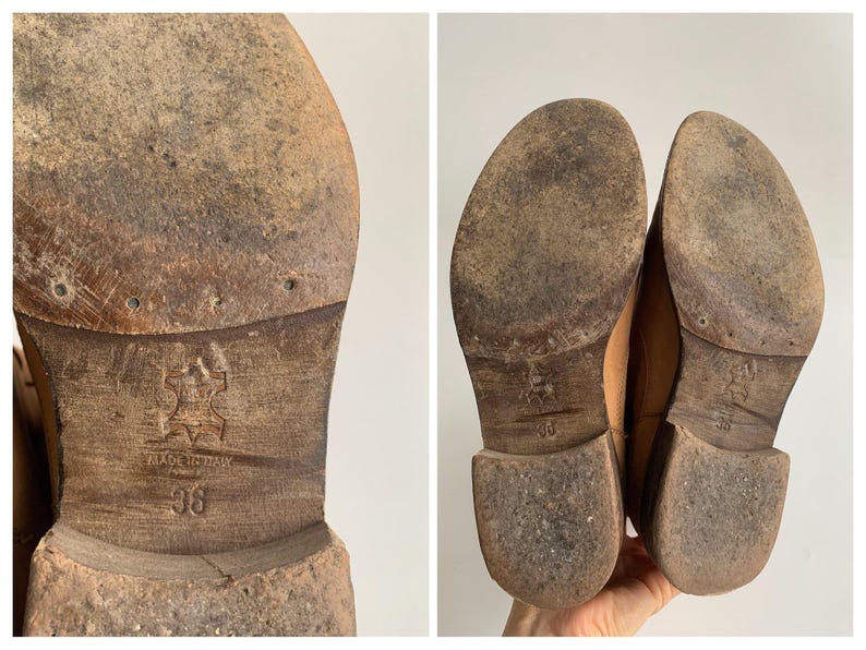 May include: Close-up of the soles of two brown leather shoes. The shoes have a worn look and are marked "Made in Italy" and "36".