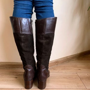 May include: Brown leather and suede knee-high boots with a block heel.