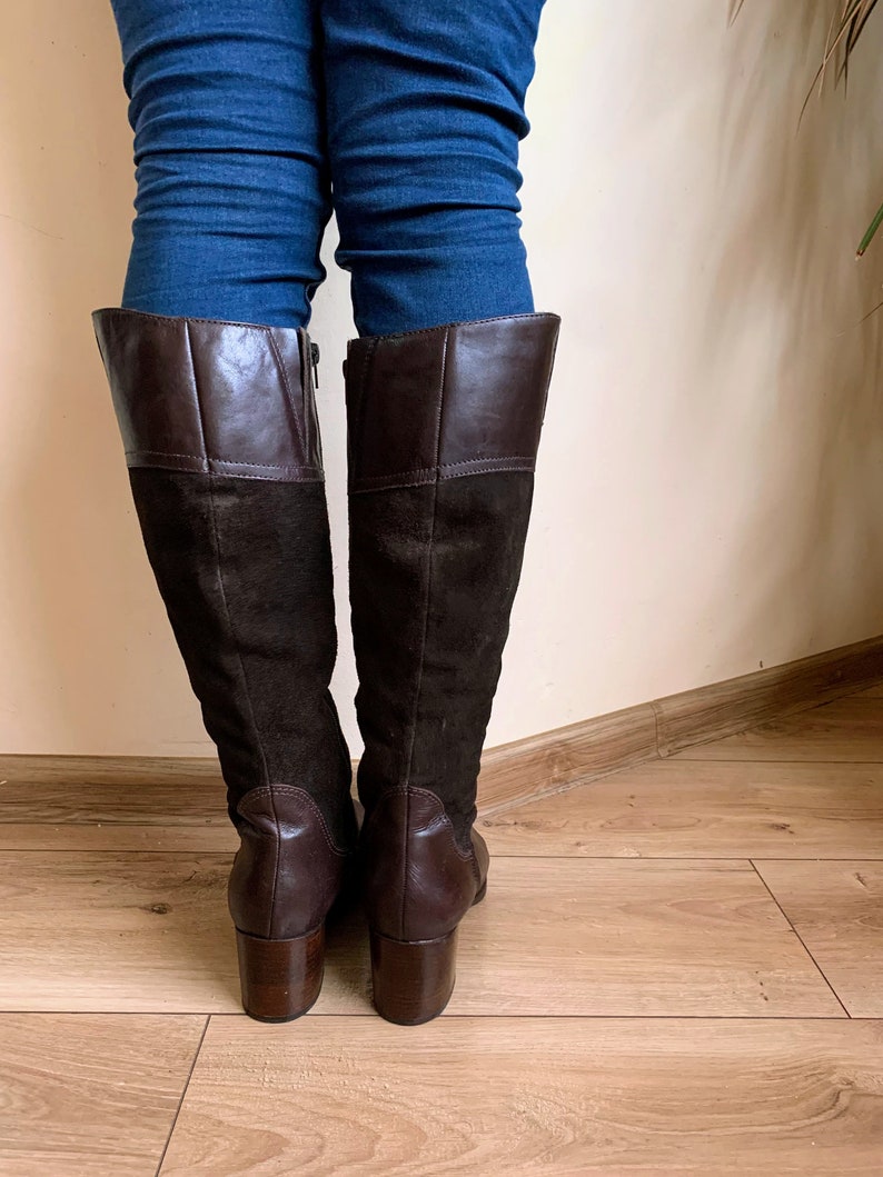 May include: Brown leather and suede knee-high boots with a block heel.
