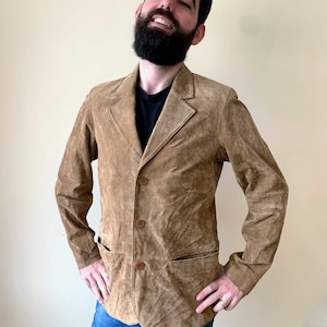 May include: A brown suede jacket with a button-up front and two pockets. The jacket has a slightly distressed look.