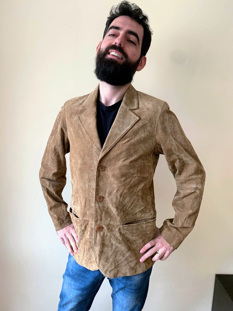 May include: A brown suede jacket with a button-up front and two pockets. The jacket has a slightly distressed look.